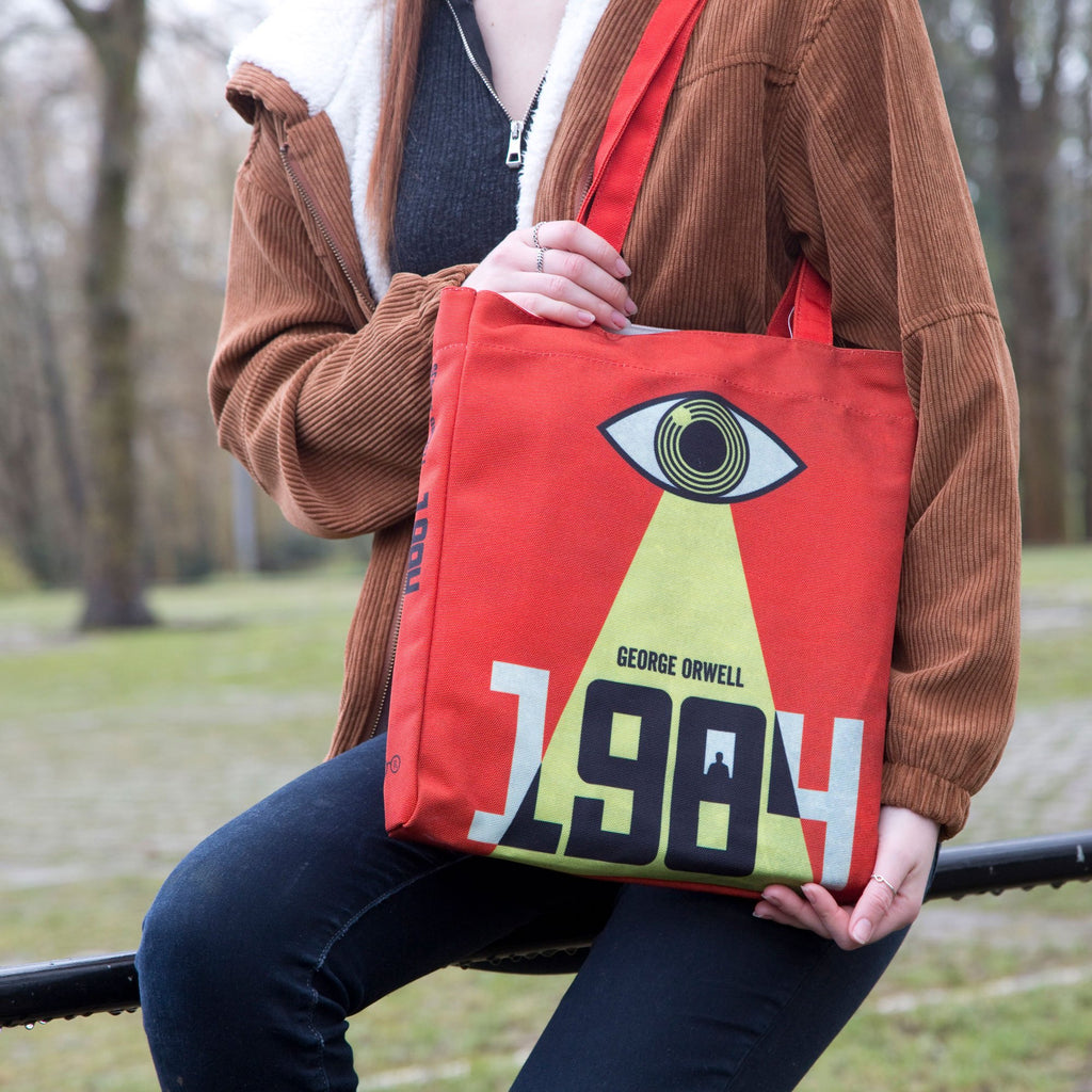 1984 Red and Yellow Tote Bag by George Orwell featuring Watchful Eye design, by Well Read Co. - Model Sitting