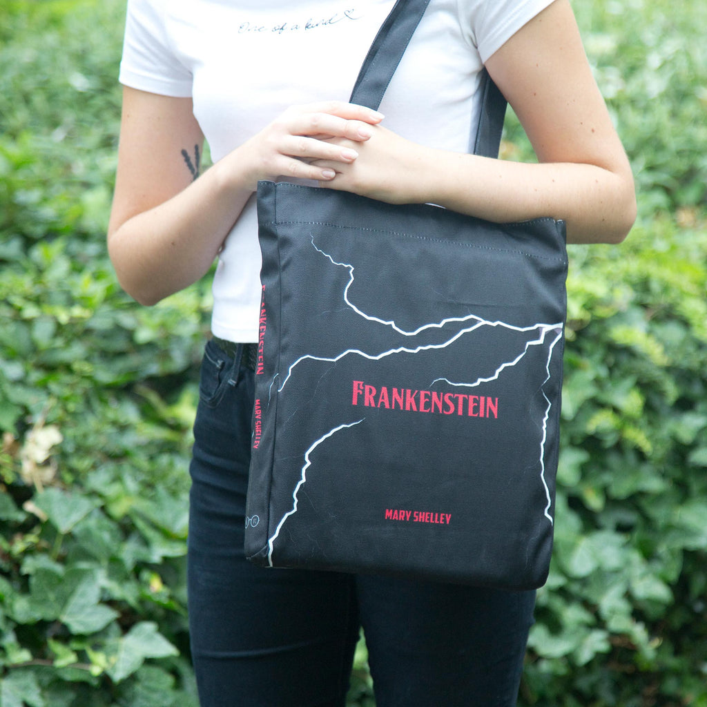Frankenstein Black Tote Bag by Mary Shelley featuring Lightning Flash design, by Well Read Co. - Girl Standing with Bag