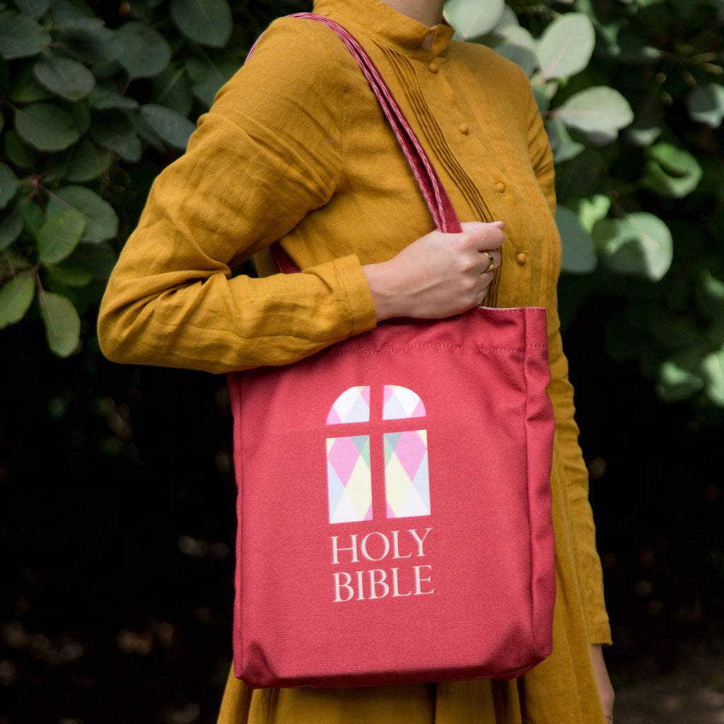 The Holy Bible Red Tote Bag by Well Read Co. featuring Stained-Glass Window design - Model in Yellow Dress